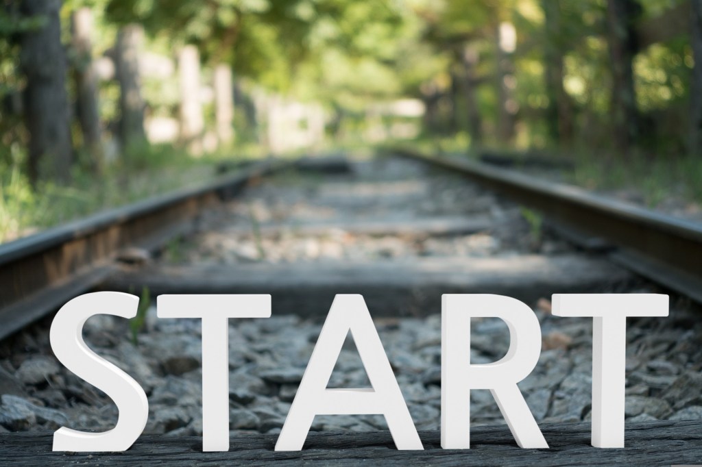 The word start with train tracks and a forest in the background